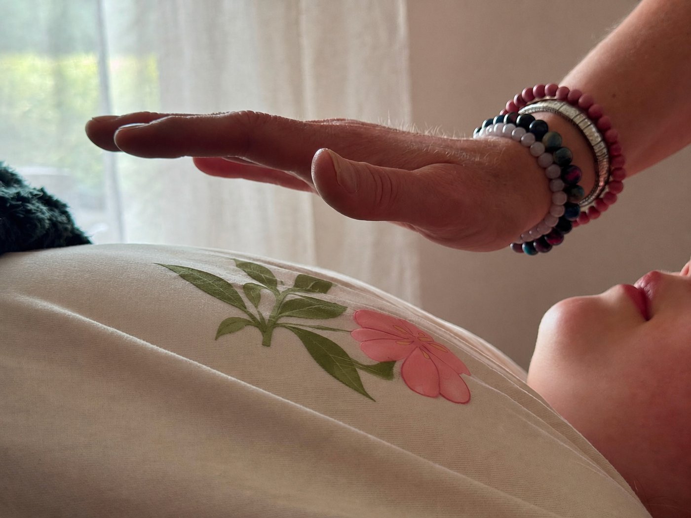 Theresa's hand held gently above a client during a Reiki session